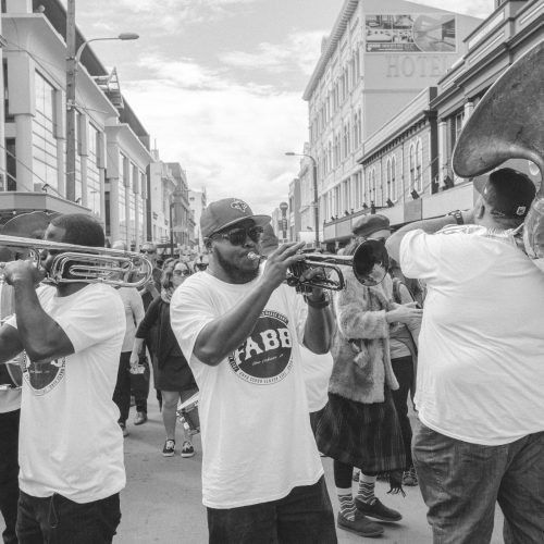 Four part brass band playing as they walk down the street
