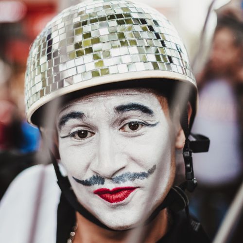 Person in white face paint, wearing a helmet decorated like a disco ball