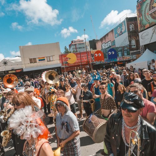 Multiple instrumentalists including drums and brass in a large crowd