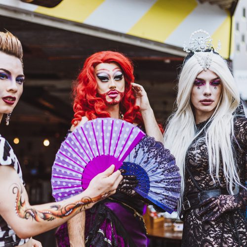 Three drag queens posing on the street