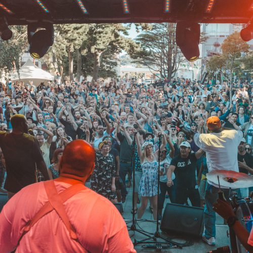 Large crowd at glover park stage waving their hands in the air