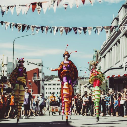 Towering Walking Creatures in colourful costume parading down the street