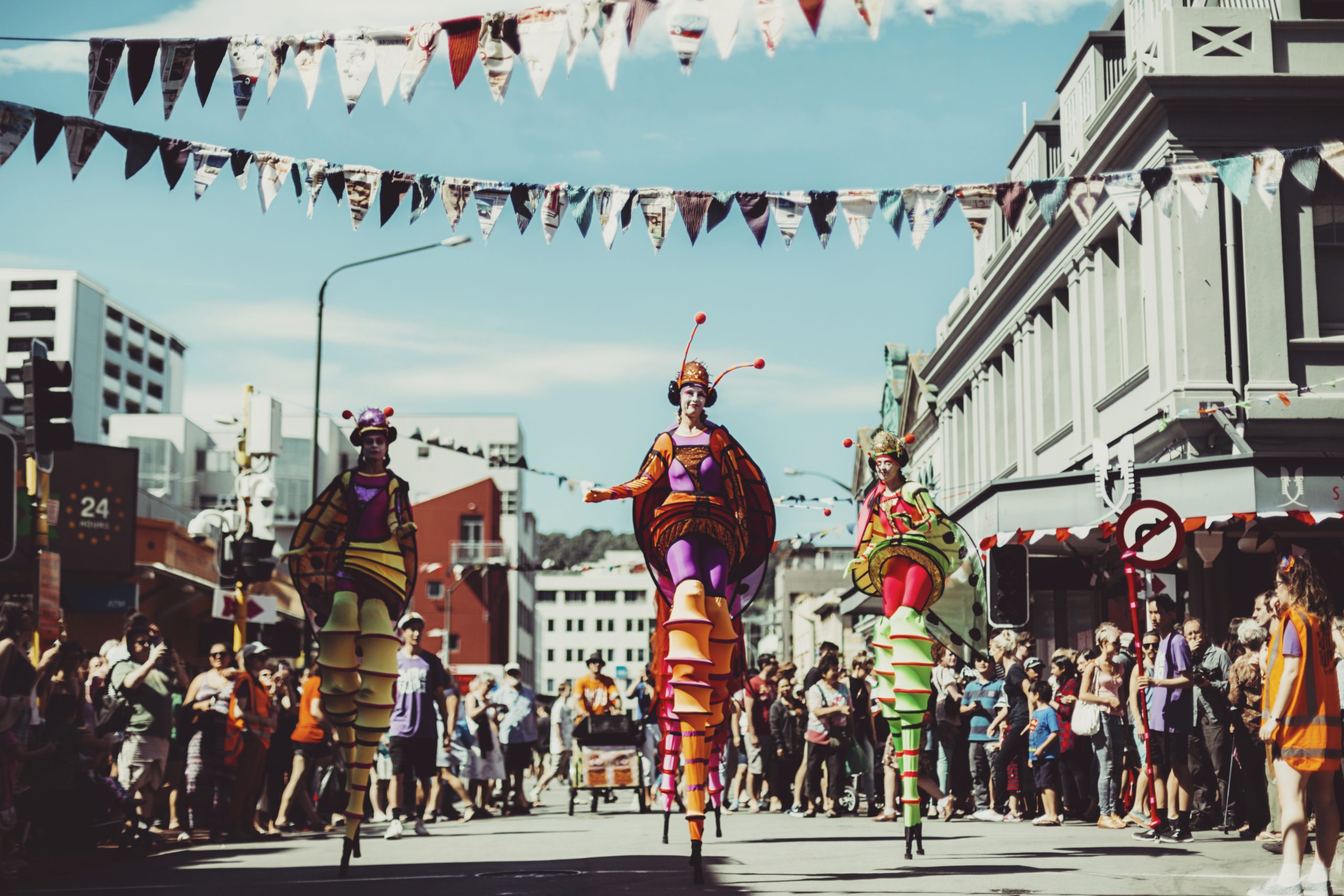 Towering Walking Creatures in colourful costume parading down the street