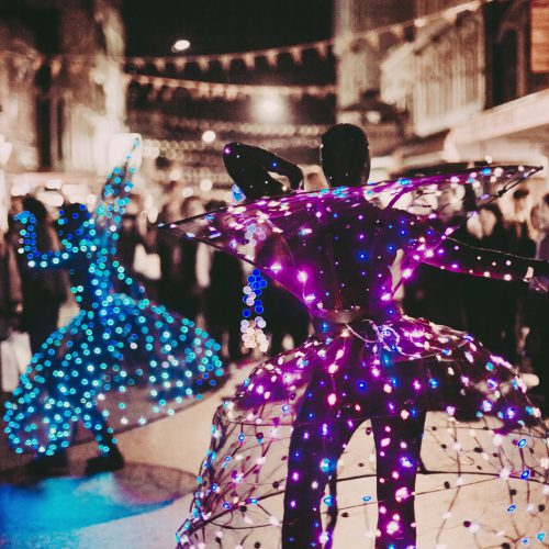 Two street performers in purple and blue light up costumes