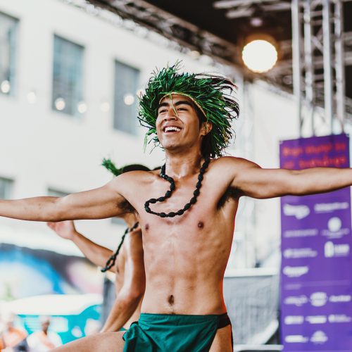 Happy dancer in a grass headdress, doing a traditional pasifika dance