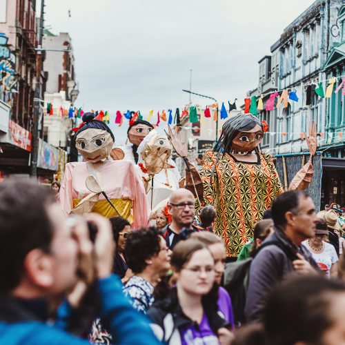 Towering giant walking puppet making their way through the Cuba Street crowds